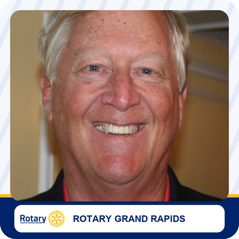 andy-devries Close-up portrait of a smiling older man in a dark blazer, affiliated with Rotary Grand Rapids.