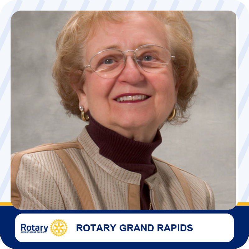 jkm-foundation-leadership Smiling elderly woman with short blonde hair and glasses, wearing a beige jacket over a dark maroon turtleneck.