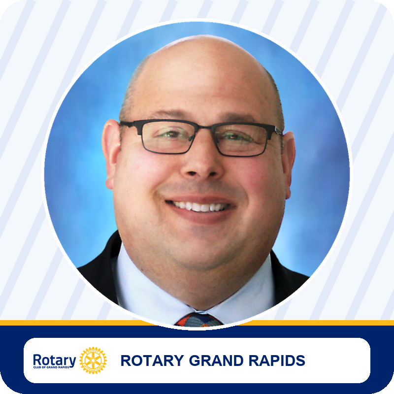 Smiling man in glasses in a circular portrait frame, Rotary Grand Rapids member.